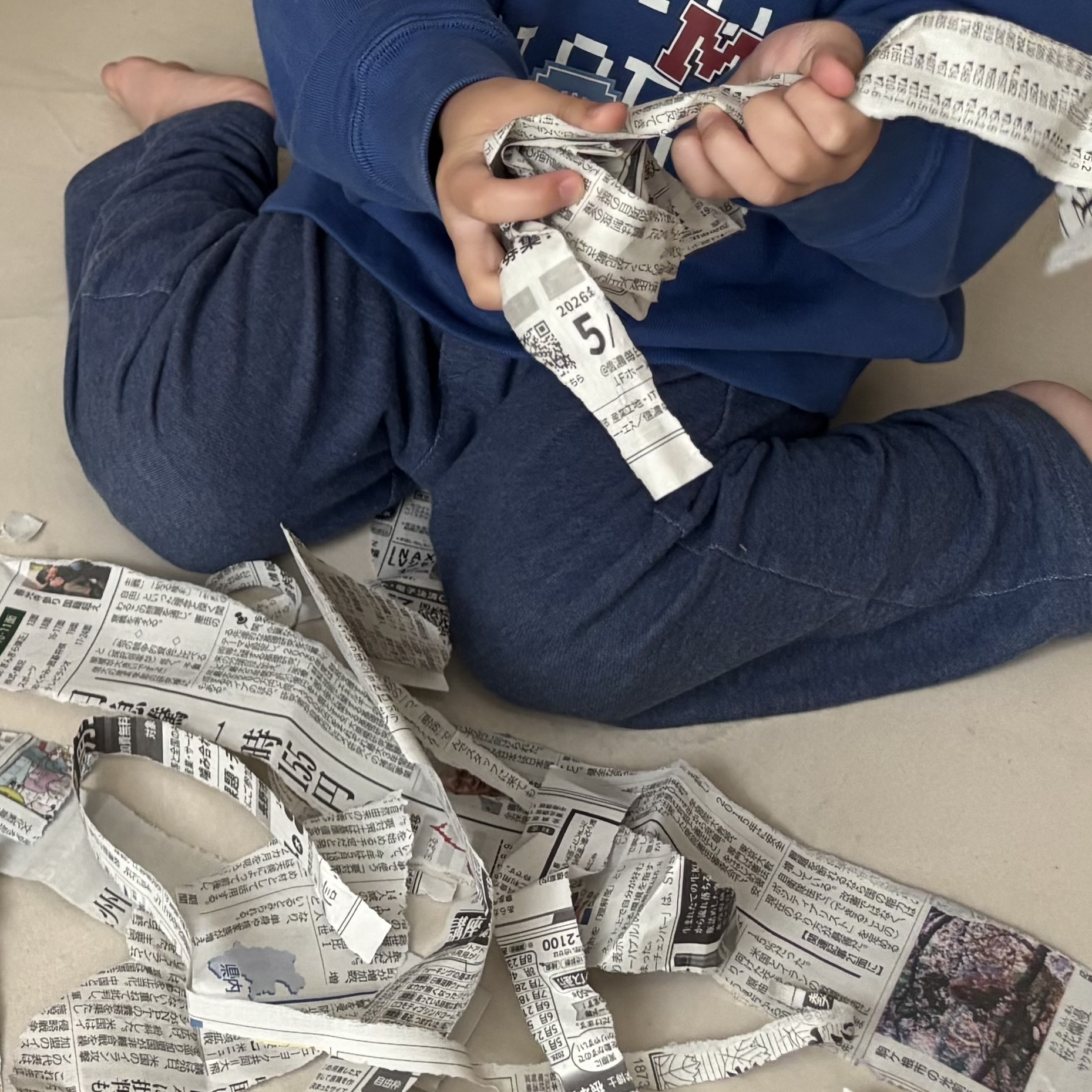 新聞紙を使って遊ぶお子さま